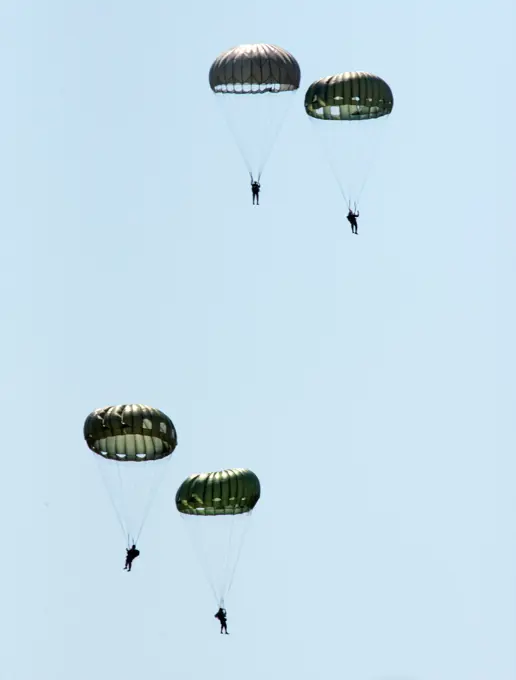 World War II paratroop reenactors float down toward their landing zone near the National Museum of the U.S. Air Force on April 27, 2022, at Wright-Patterson Air Force Base, Ohio. A total of 17 reenactors jumped from two WWII-era C-47 Skytrains that had also dropped paratroopers over Normandy on D-Day.