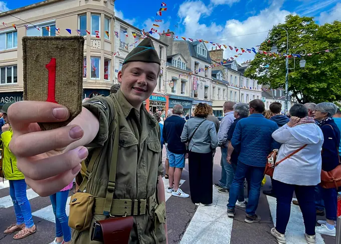 A kid from Carentan holds up a 1st Infantry Division patch during a D-Day commemoration parade at Carentan, France, June 6, 2022. This year, U.S. Army Europe and Africa commemorates the 78th anniversary of D-Day, the largest multi-national amphibious landing and operational military airdrop in history, and highlights the U.S.' steadfast commitment to European allies and partners.