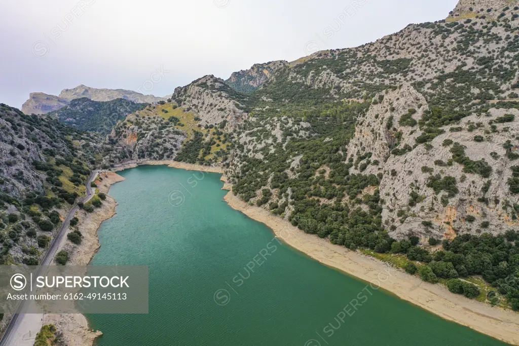 Aerial view of the Torrent de Gorg Blau river dam with its green water, mountain rocks and vegetation surrounding it in Escorca, Balearic Islands, Spain.