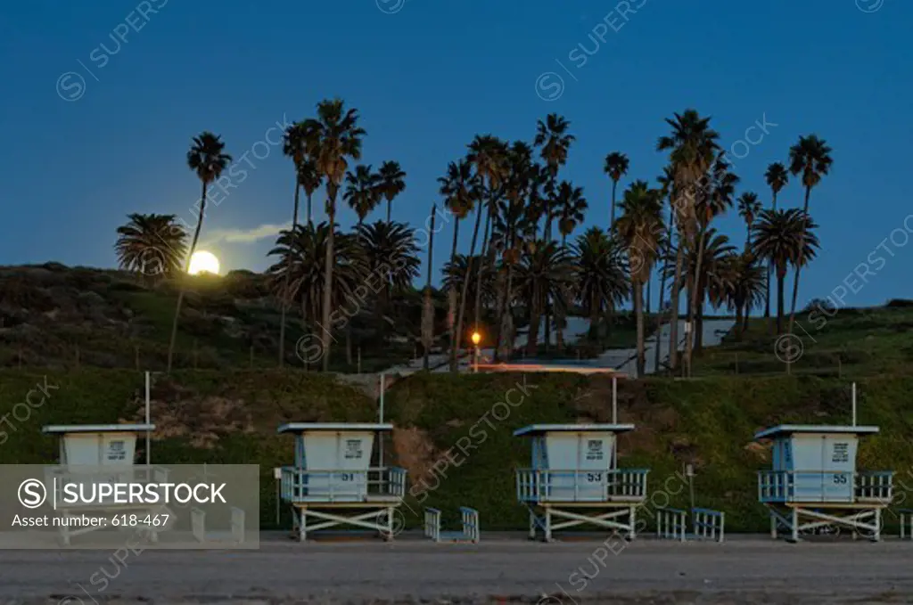 USA, California, Los Angeles, Westchester, Winter moonrise over Dockweiler Beach, where unused life guard booths have been placed together in waiting for summer season