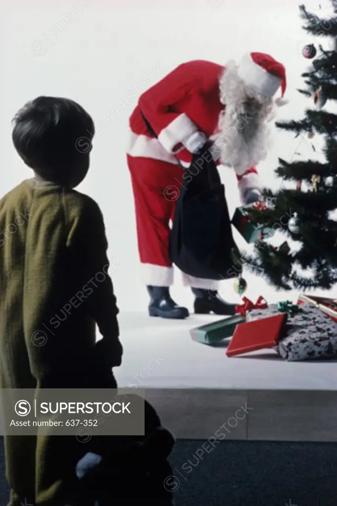 Young boy looking at Santa Claus near a Christmas Tree