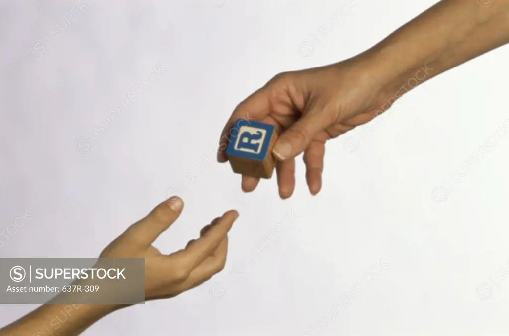 Person handing a toy block to another person