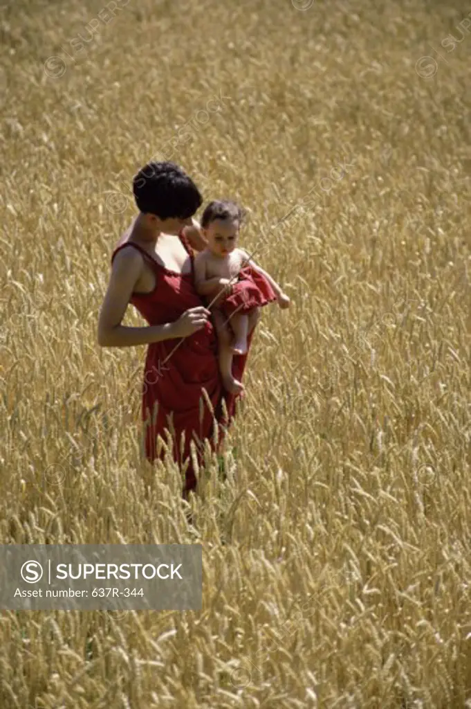 Mother holding her baby boy in a field