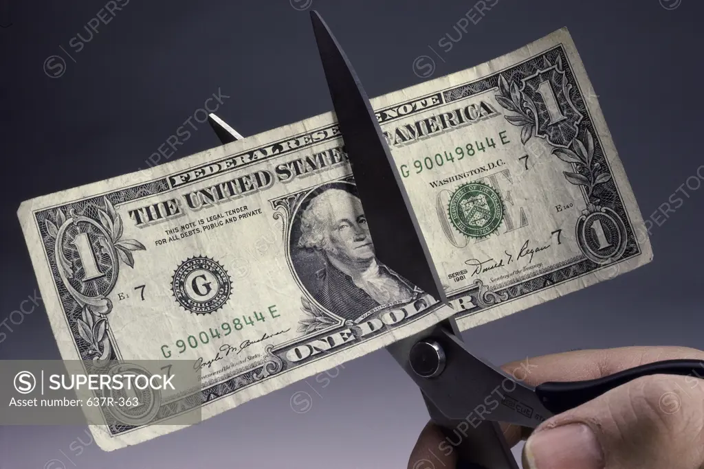 Person cutting a bank note with a pair of scissors