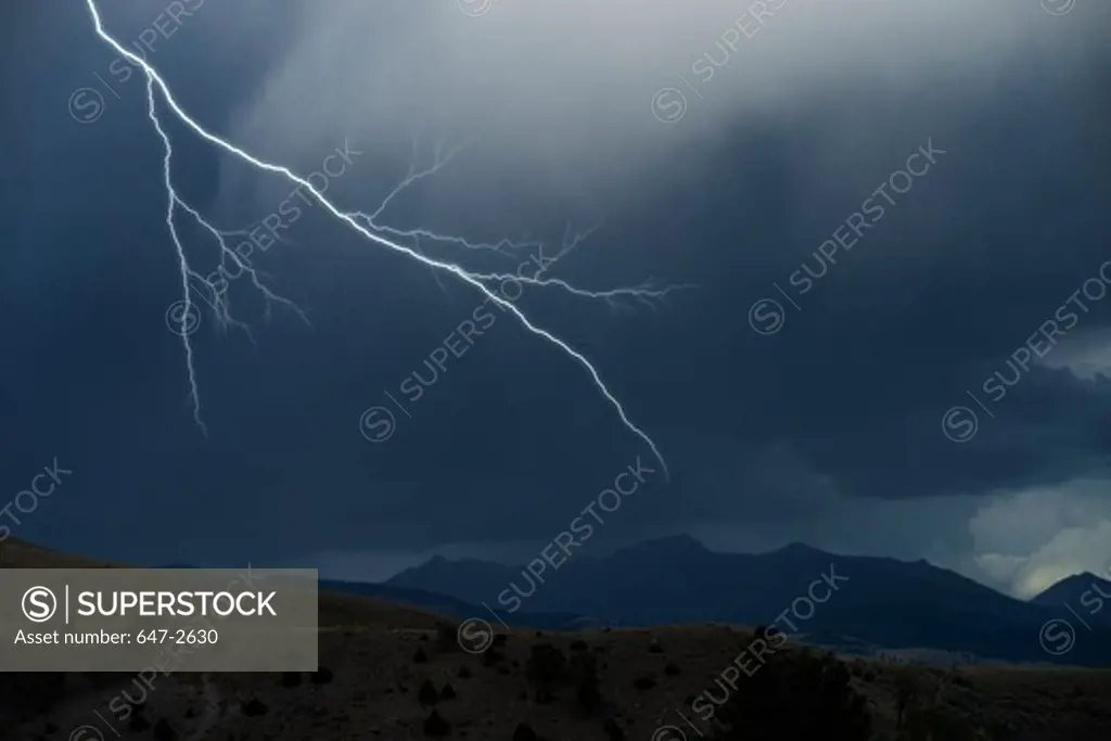Lightning in clouds with mountains below