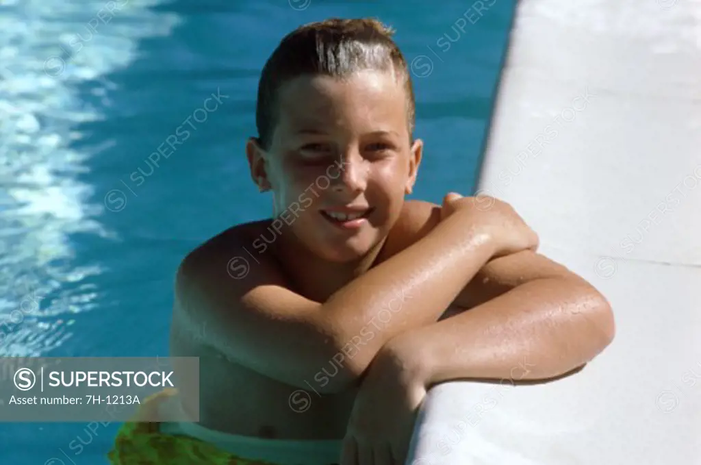 Portrait of a boy leaning on the ledge of a swimming pool