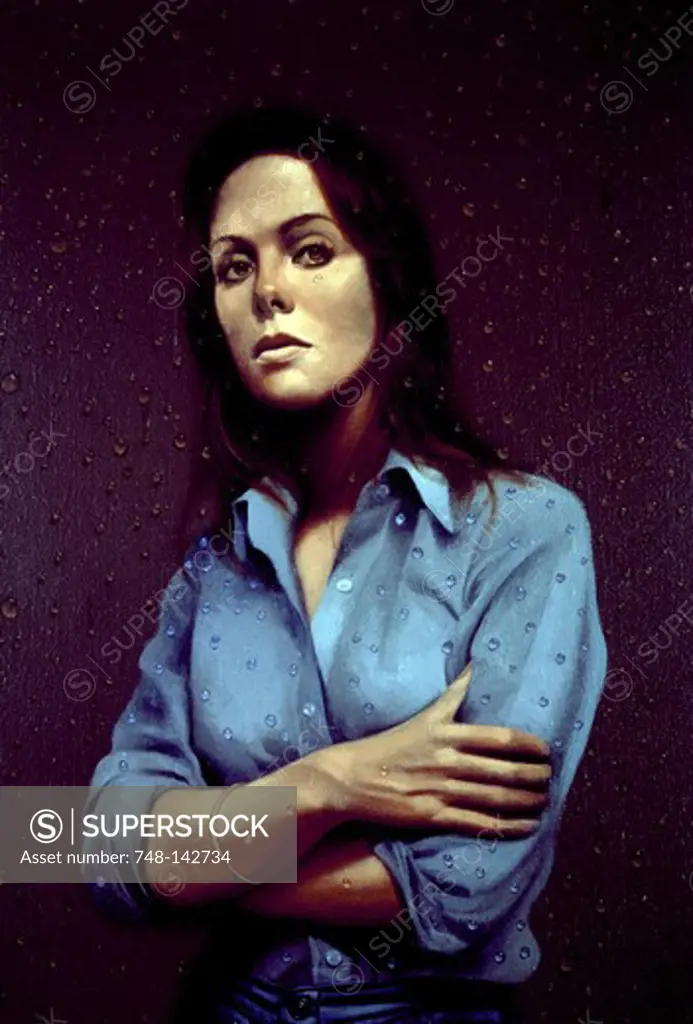 Portrait of sad young woman standing behind window with raindrops