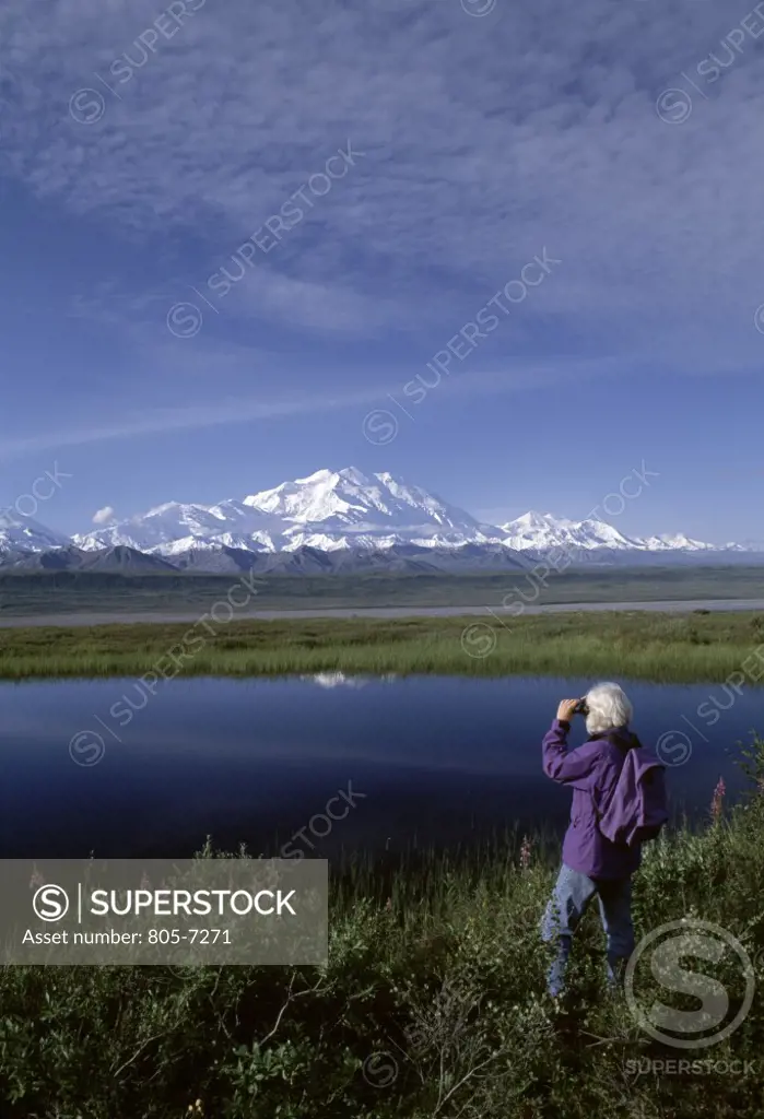 Tourist looking at scenery through binoculars, Mt McKinley, Denali National Park, Alaska, USA