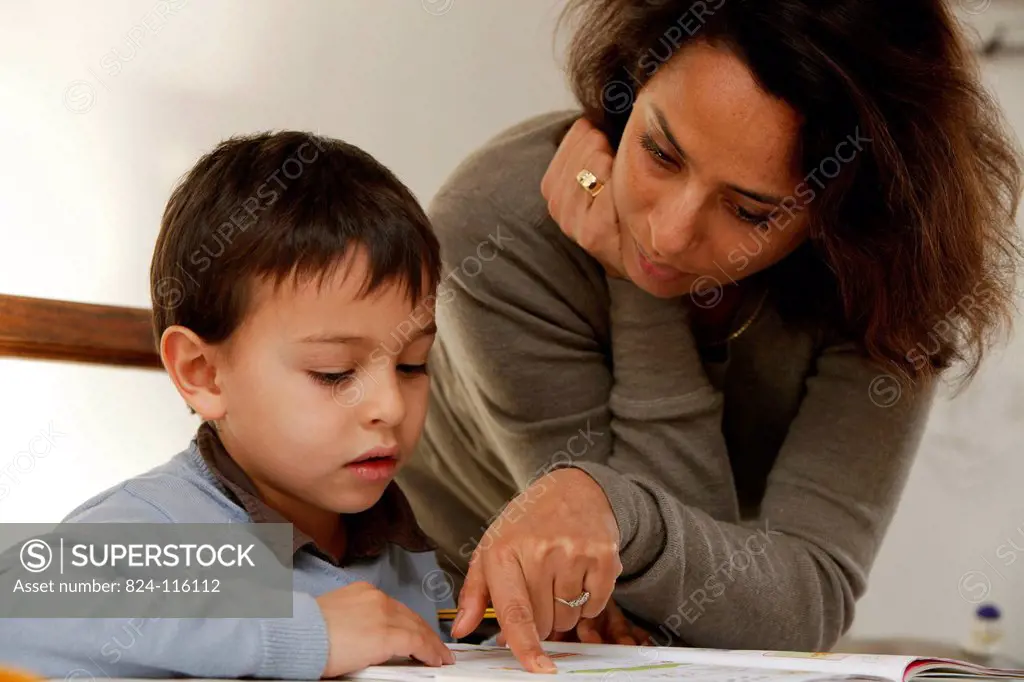 Mother helping a 6_year_old boy with his homework