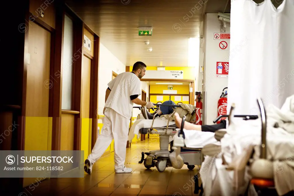 Reportage at night in the A&E department of Robert Ballanger general hospital, France. A stretcher bearer settles patients in the corridor.