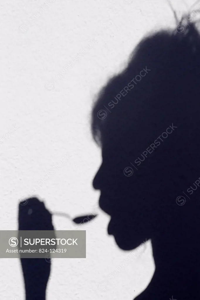 Shadow of a woman eating with a spoon.