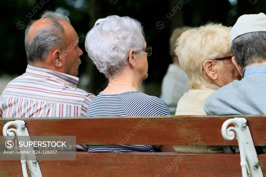 Elderly back sitting on a bench.