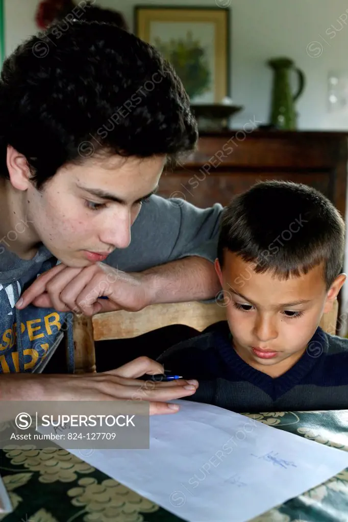 Teenager helping his brother with his homework