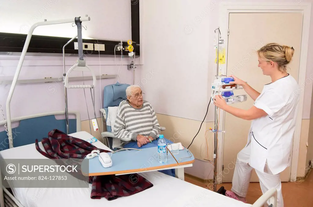 Reportage in the Geriatrics service in Saint-Vincent de Paul hospital in Lille, France. A nurse adjusts a patients syringe pump in his hospital room.