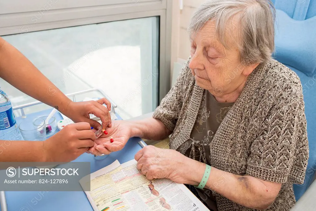Reportage in the Follow-up Care and Rehabilitation service of Saint-Philibert hospital in Lille, France. A nurse gives a patient medicine in her hospi...