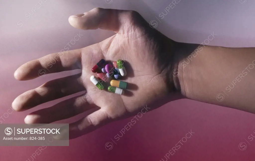 Close-up of a person's hand holding pills and capsules