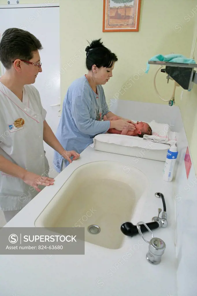 Photo essay at the maternity of Rouen hospital, France. Nursery. Child care aid explains to the young mother how to make the daily care and the toilet...