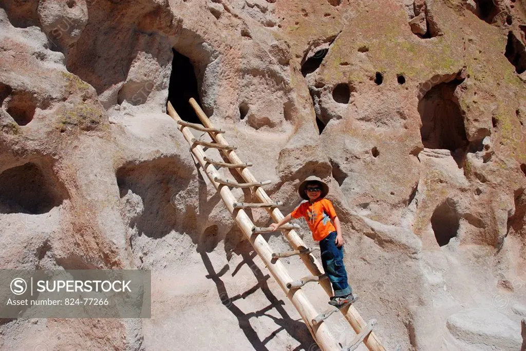 6_year_old boy climbing a troglodyte housing of the Bandelier National Monument, New mexico, USA. These houses were inhabited by an ancient amerindian...