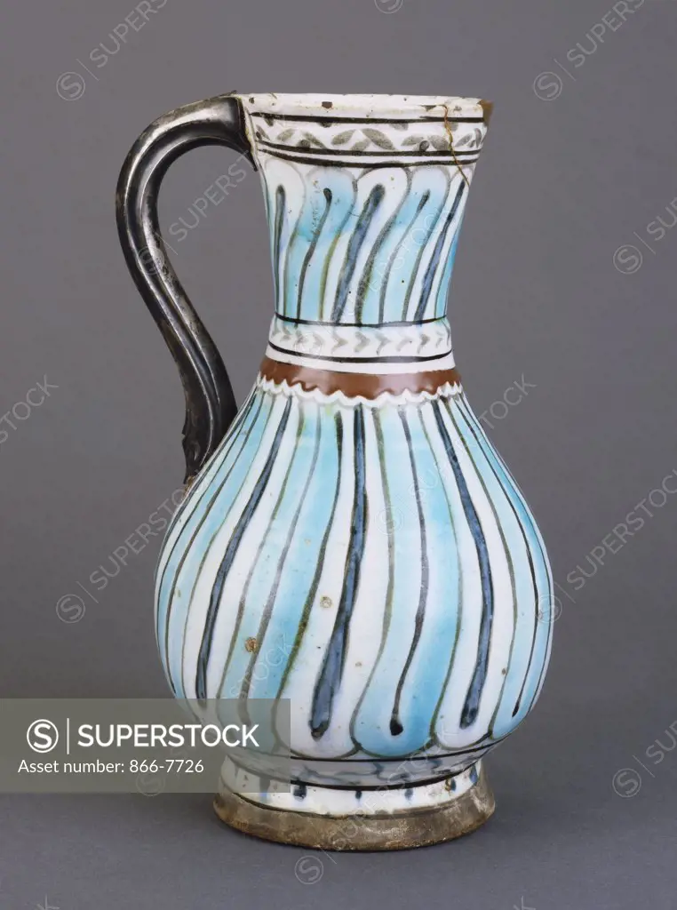 An Iznik pottery jug, the white ground painted with turquoise and dark blue stripes outlined in black. 25.5cm high.