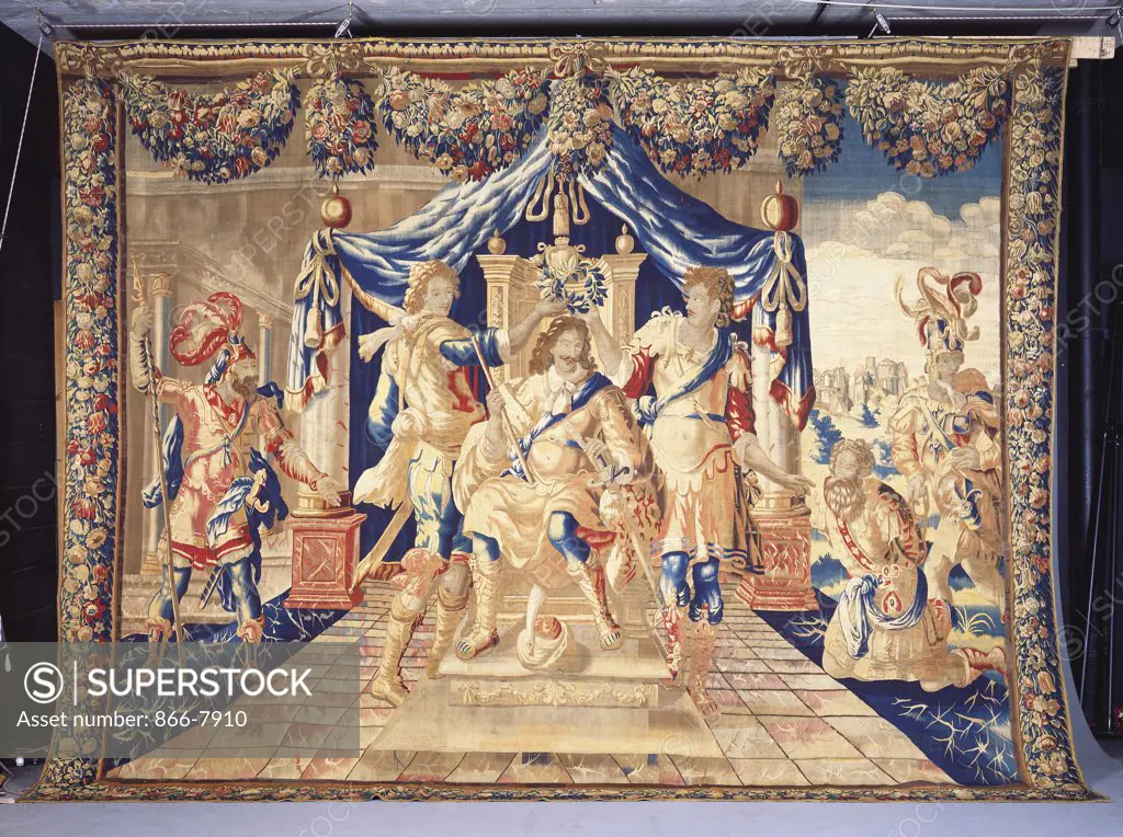 A Brussels historical tapestry, woven in wools and silks, depicting an enthroned King under a canopy, being crowned with a laurel wreath by two courtiers. Late 17th century. 377cm x 480cm.