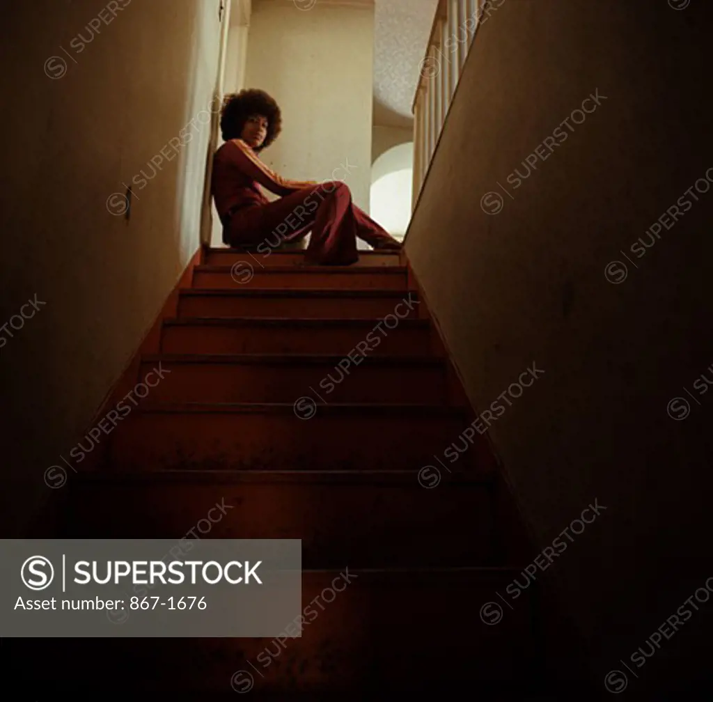 Low angle view of a young woman sitting at the top of a staircase