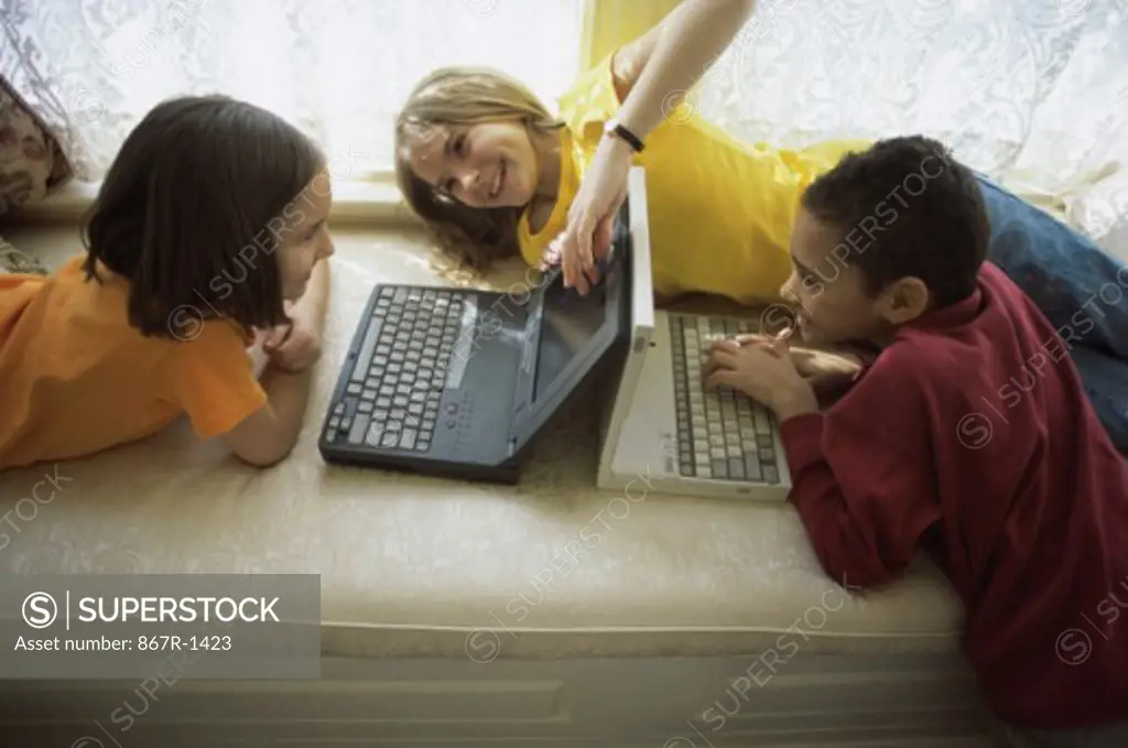 Two girls and a boy using laptops