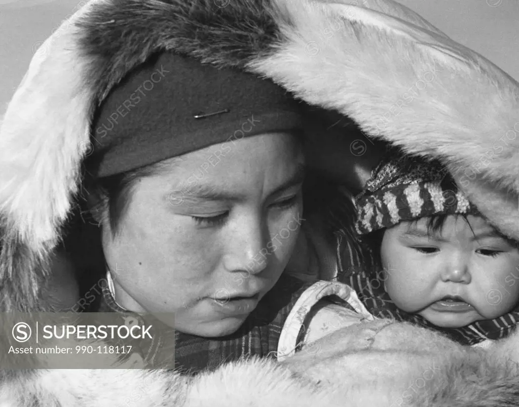 Close-up of a female Eskimo with her child in a fur coat