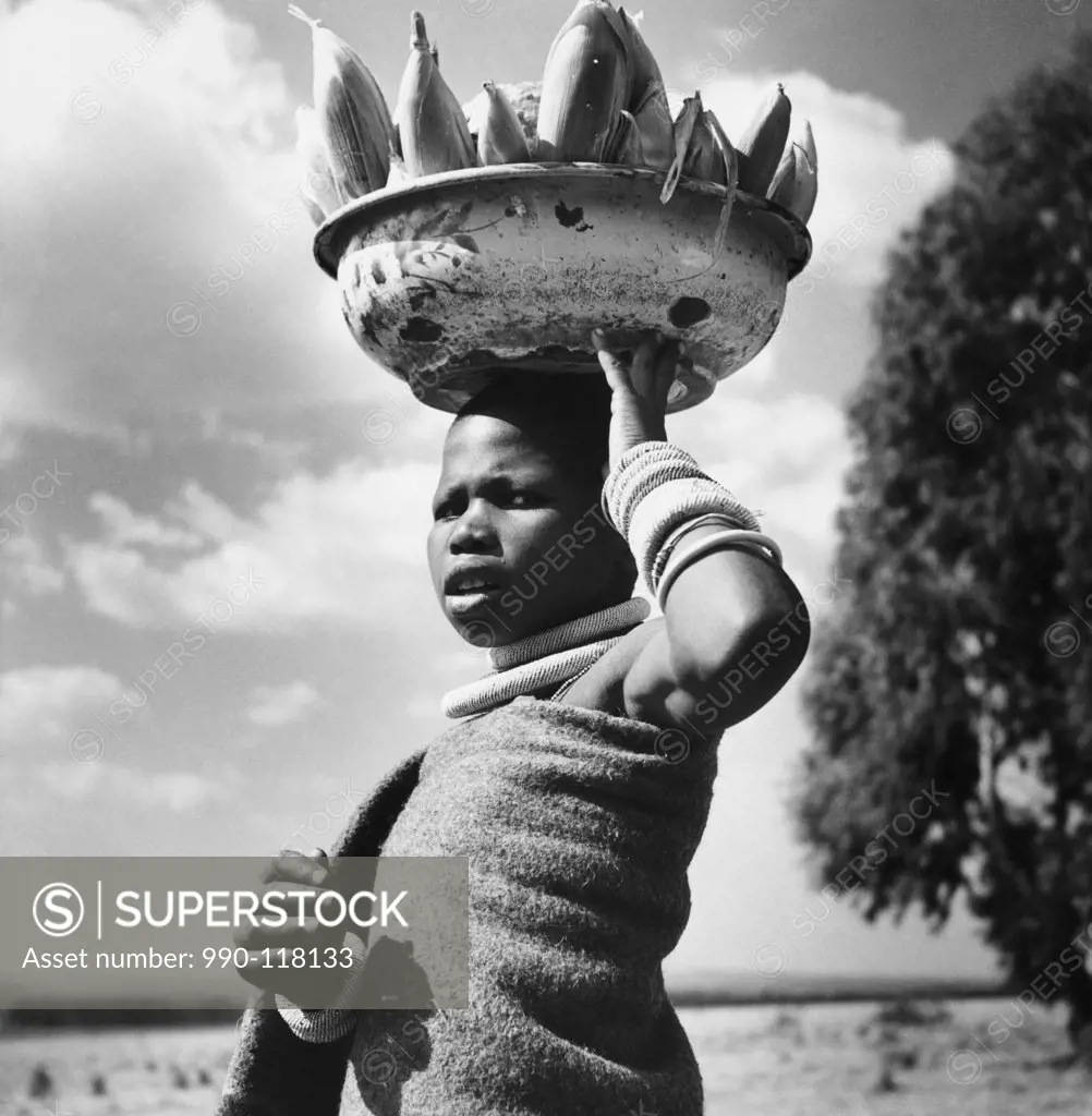 Girl carrying corn and melons in a tub, South Africa
