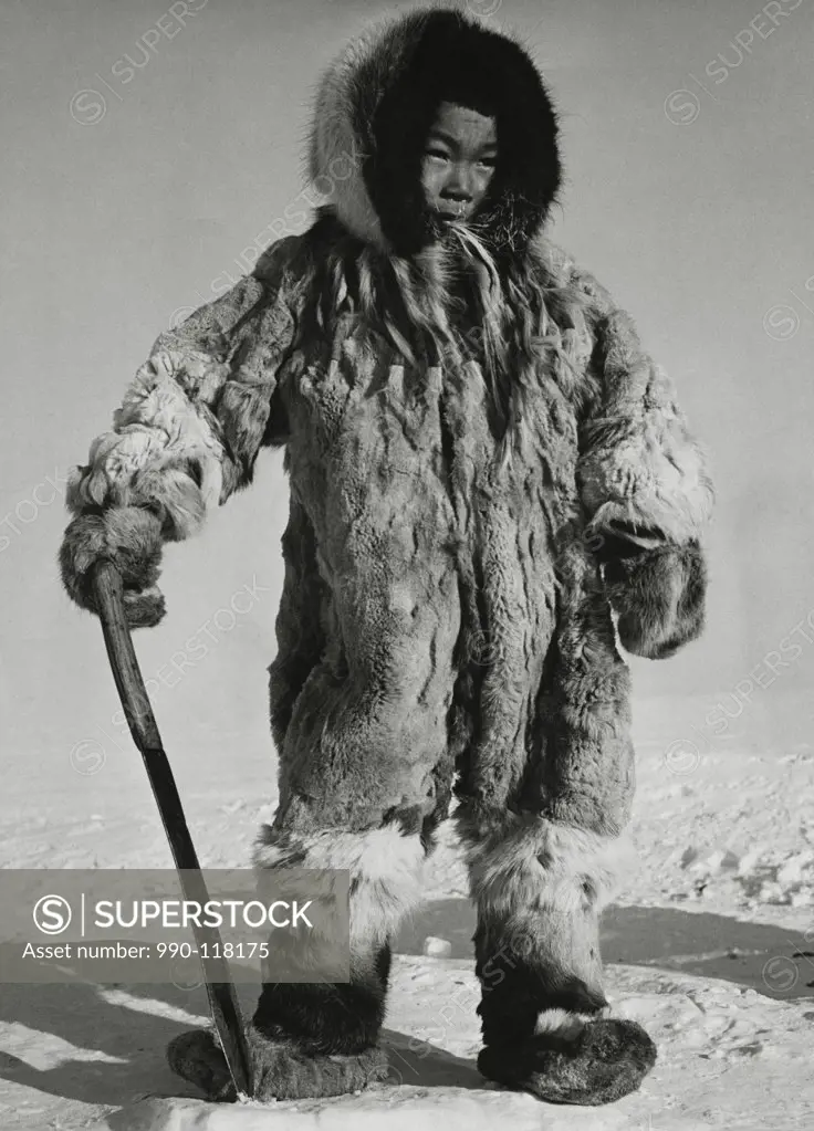Eskimo boy standing on ice and holding a knife