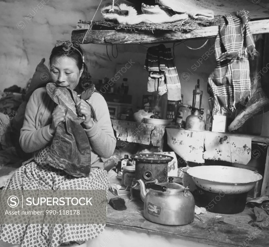 Mid adult Eskimo woman biting a sealskin boot