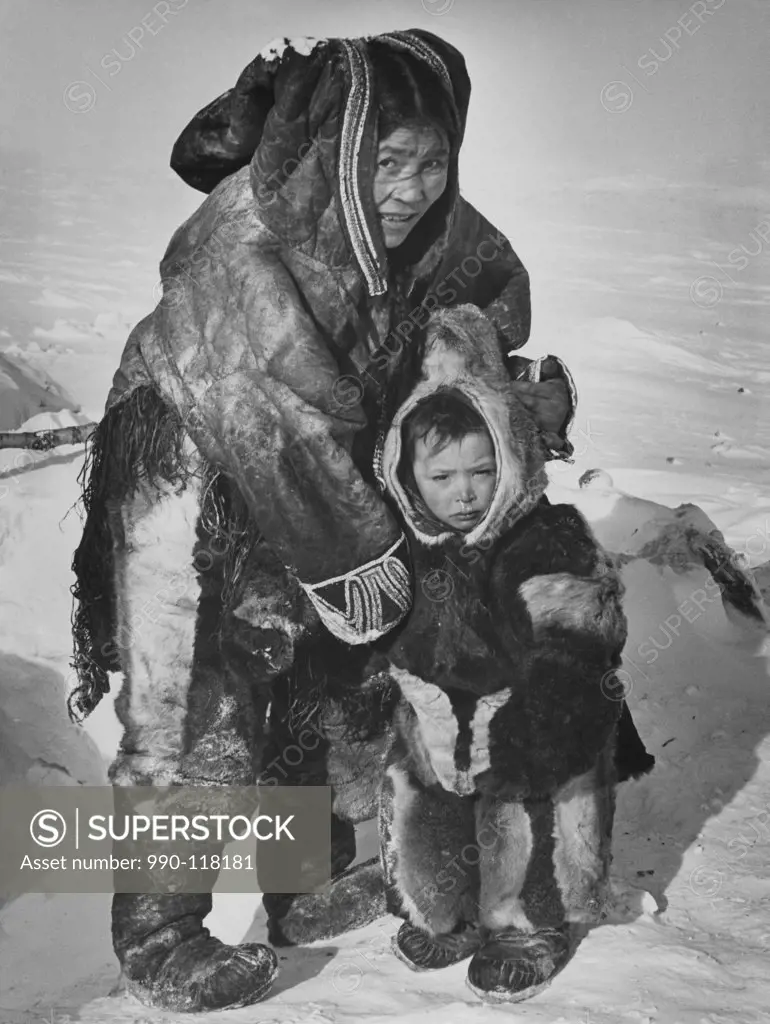 Mid adult Eskimo woman with her son standing on a polar landscape, Northwest Territories, Canada