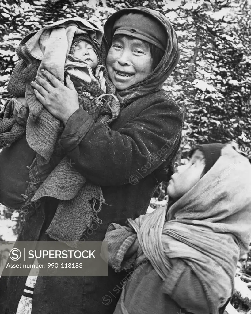 Mid adult woman holding her baby with her daughter standing beside her