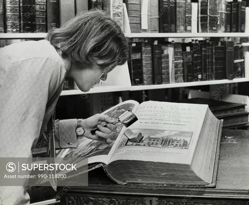 Young man examining a miniature Bible in a library
