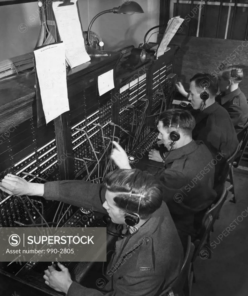 Four military personnel operating a telephone switchboard