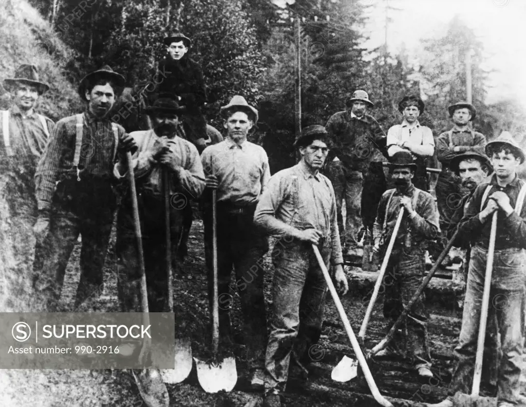 Group of manual workers standing and holding shovels