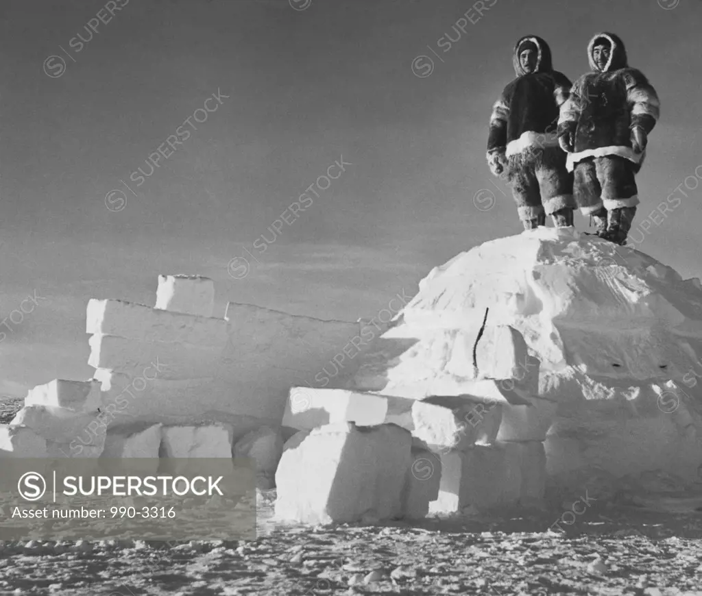 Low angle view of two men standing on an igloo