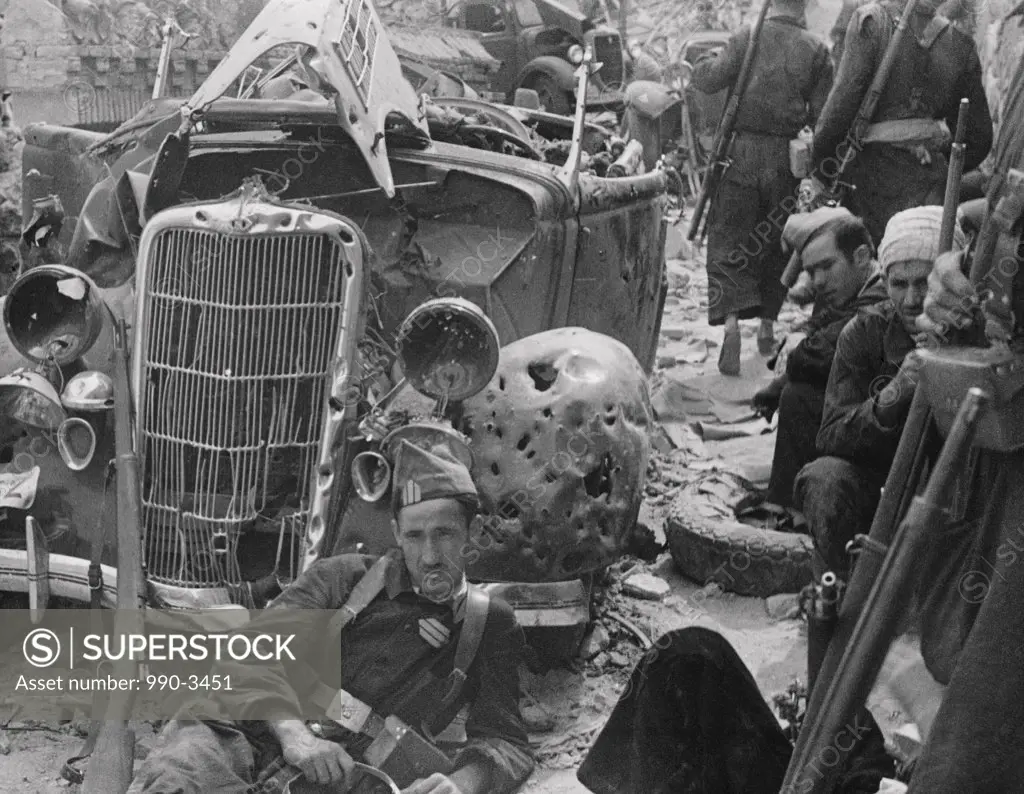 Group of soldiers near a damaged car during a war, Spanish Civil War