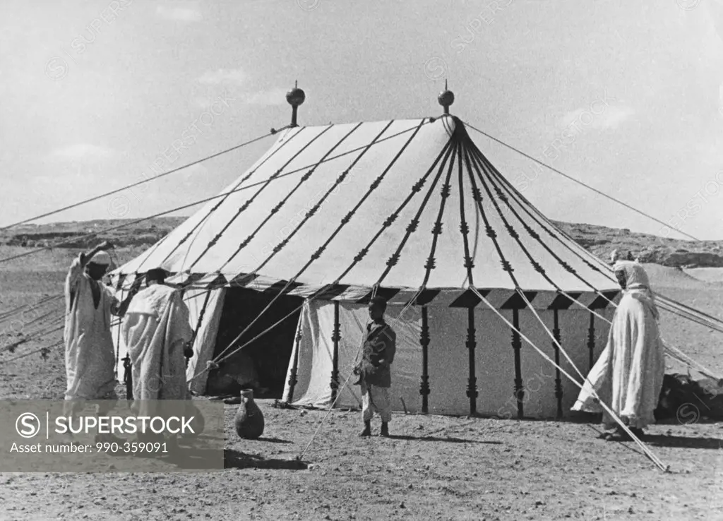 Men building tent on desert, boy watching them