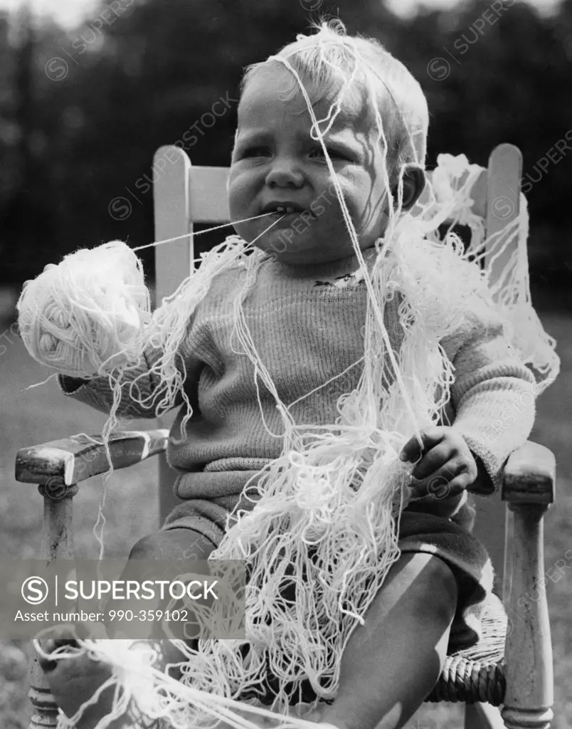 Baby boy covering by wool and holding ball of wool