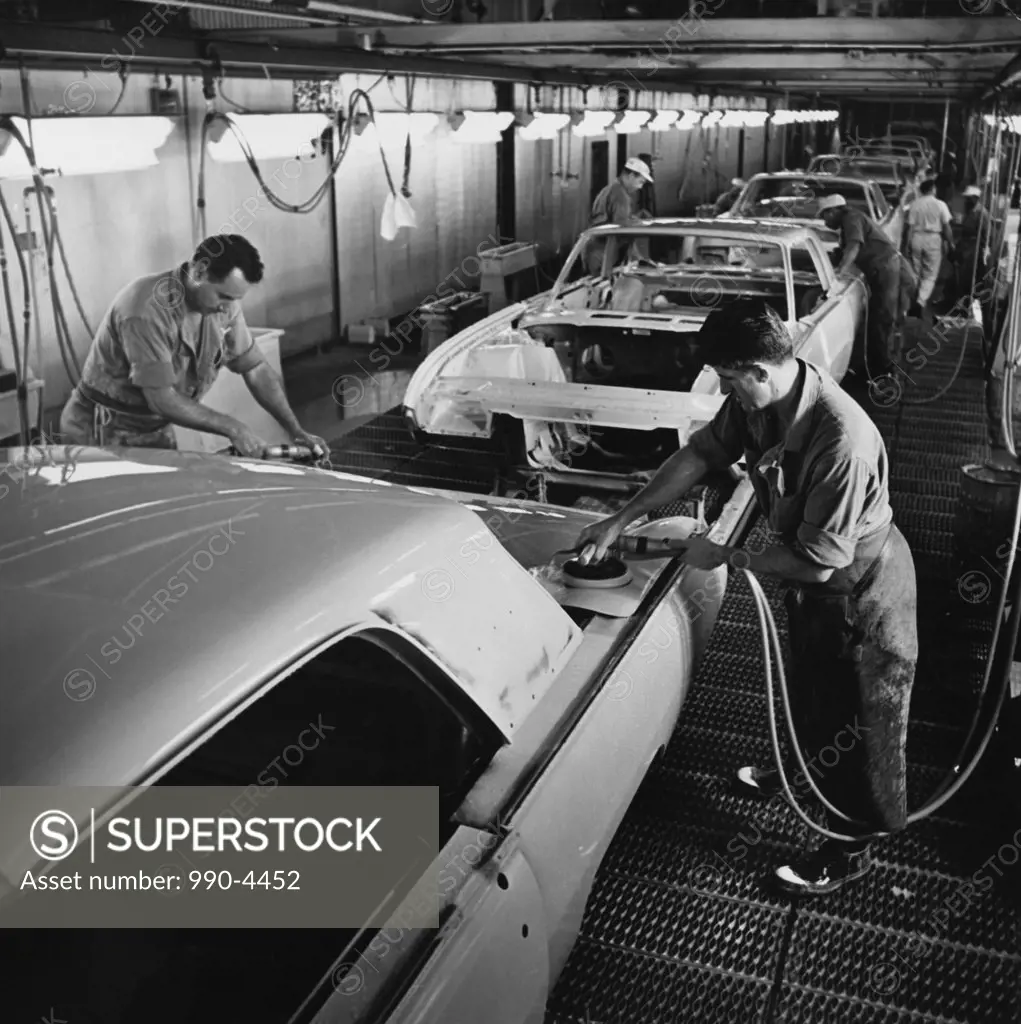 Two male workers working in a car assembly plant