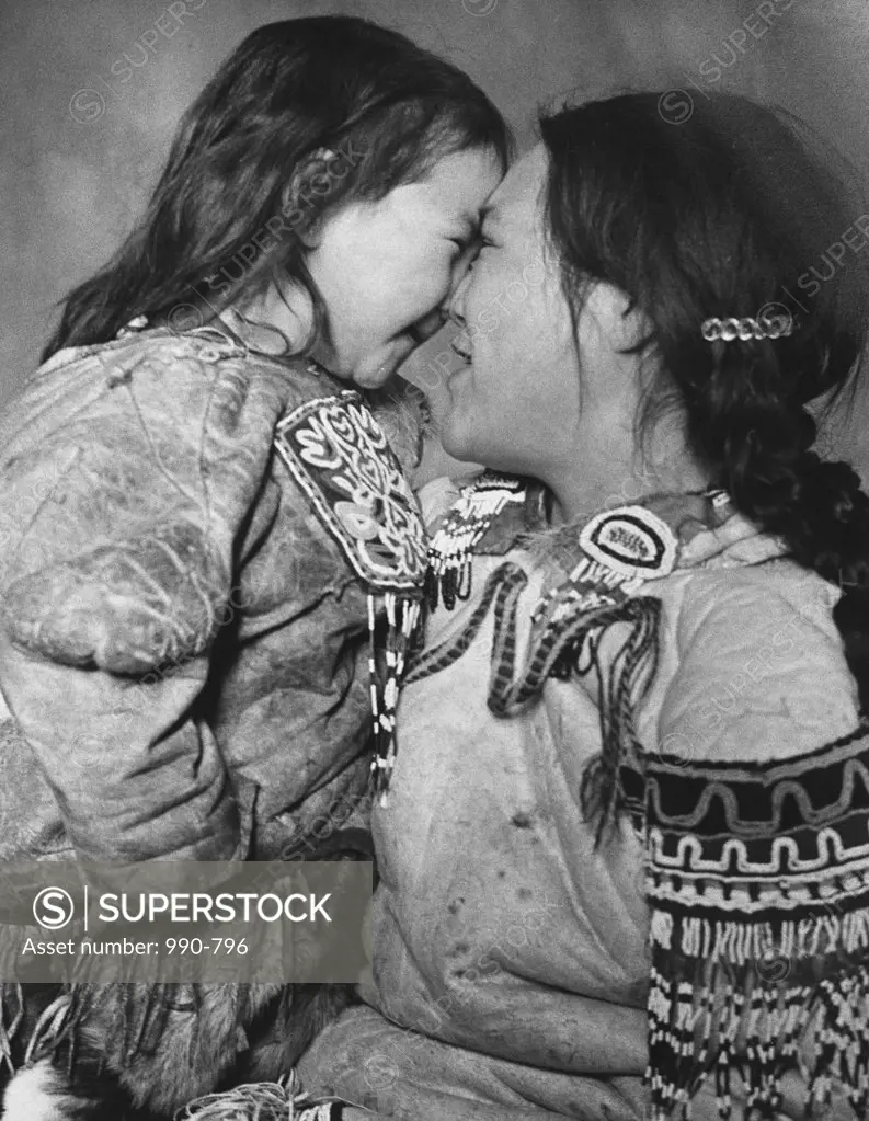 Mid adult Eskimo woman and her daughter rubbing noses